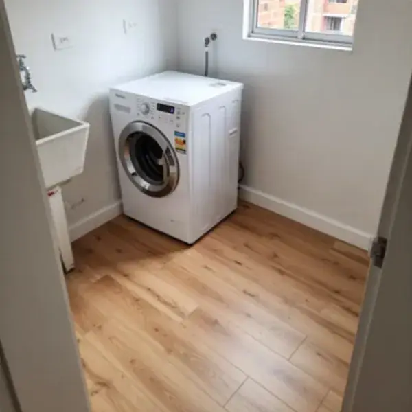 Piso laminado continuo en zona de ropas con lavadora