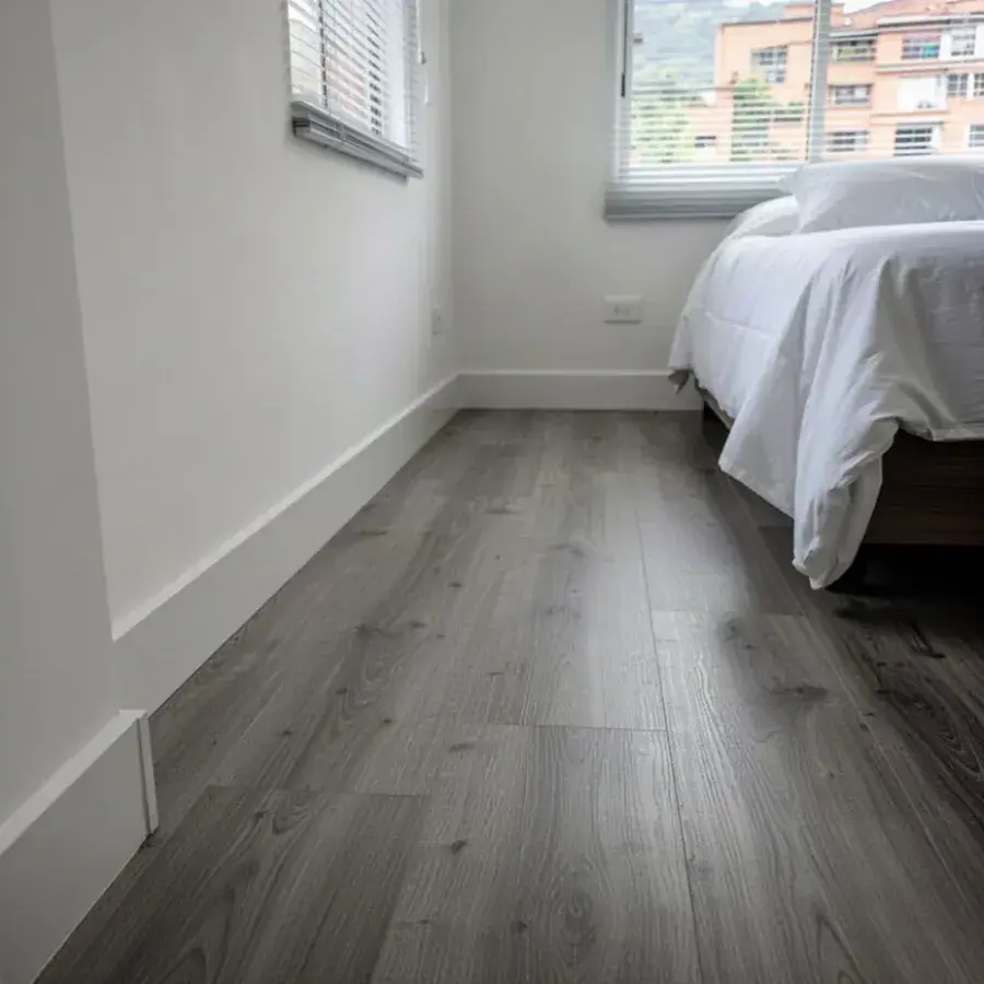 Piso laminado gris con zócalo blanco en alcoba