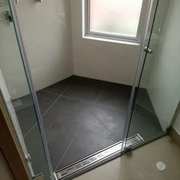 Porcelanato gris antideslizante en ducha con rejilla lineal