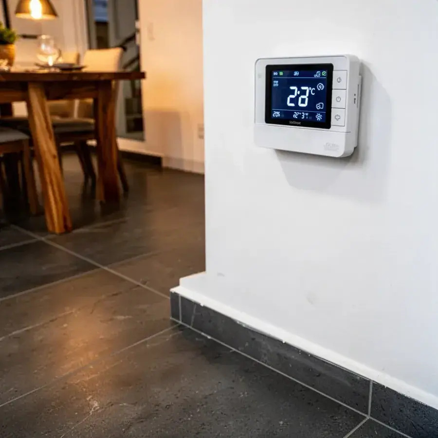 Termostato de piso radiante sobre porcelanato gris en comedor